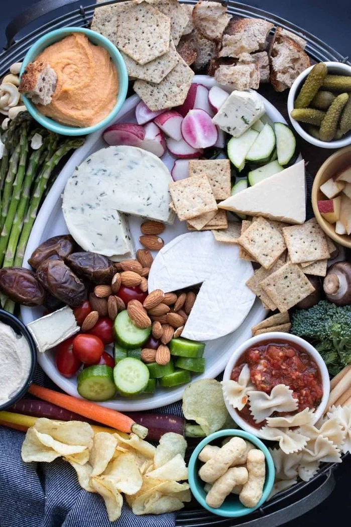 crackers hummus pickles cheeses vegan platter what is charcuterie nuts veggies on round tray