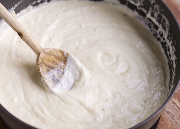 creamy garlic sauce cooking in black saucepan best pasta dishes stirred with wooden spoon