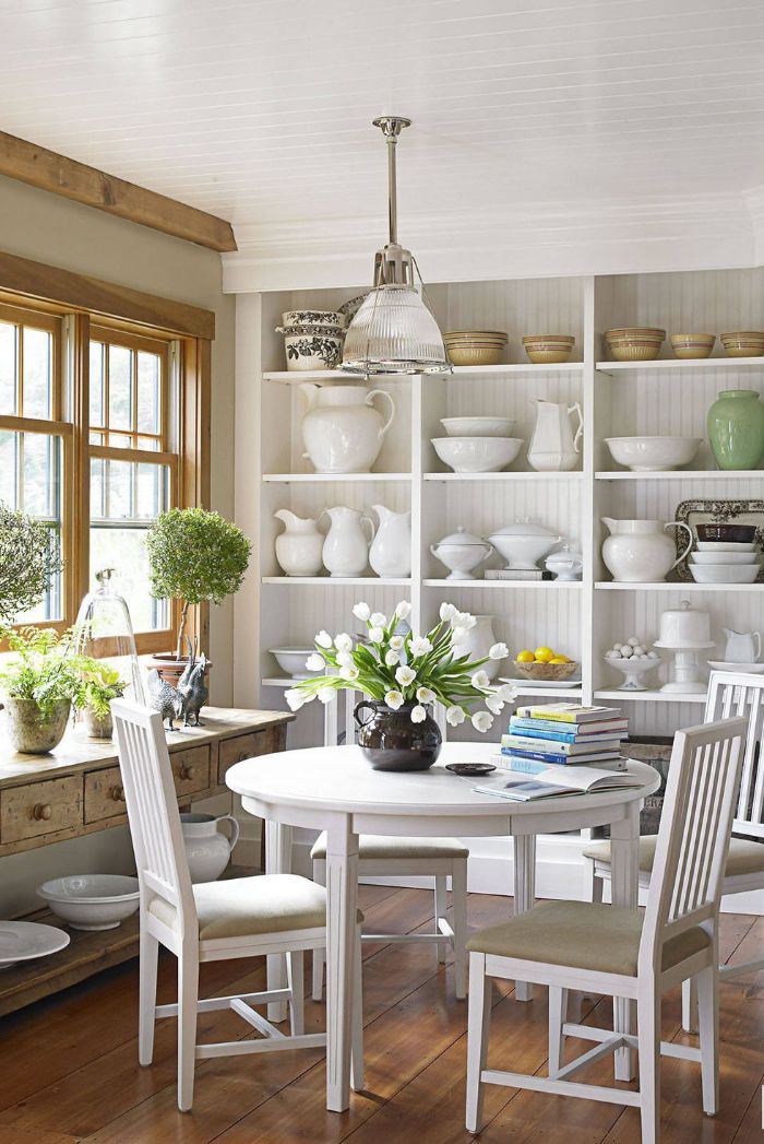 dining room with round table four chairs open shelving kitchen white backdrops bouquets of flowers