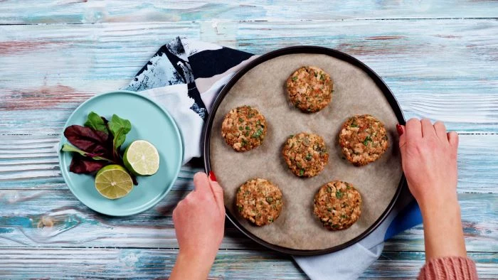 easy appetizers for a crowd six salmon meatballs arranged on paper lined baking tray placed on white wooden surface