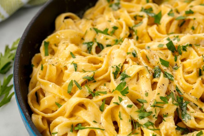 fettucine alfredo with creamy sauce homemade pasta recipe garnished with chopped parsley in black plate