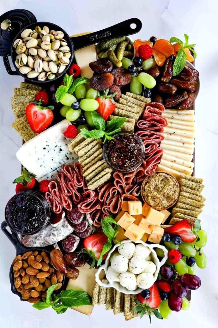 fruits veggies meats cheeses crackers nuts condiments arranged on wooden board how to make a charcuterie board