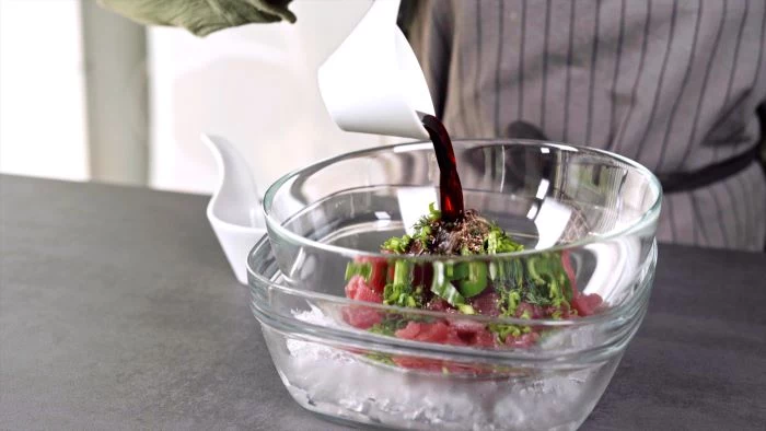 glass bowl placed on top of another glass bowl filled with ice appetizers for a crowd tuna tartare mixture