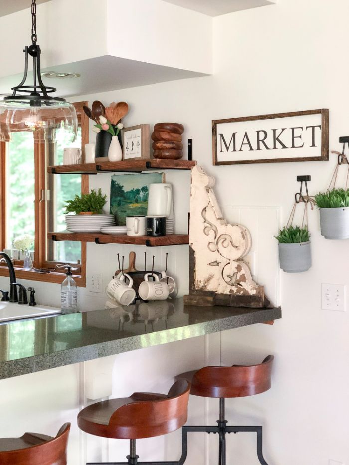 granite countertop wooden bar stools floating kitchen shelves natural wood shelves with white plates farmhouse decor