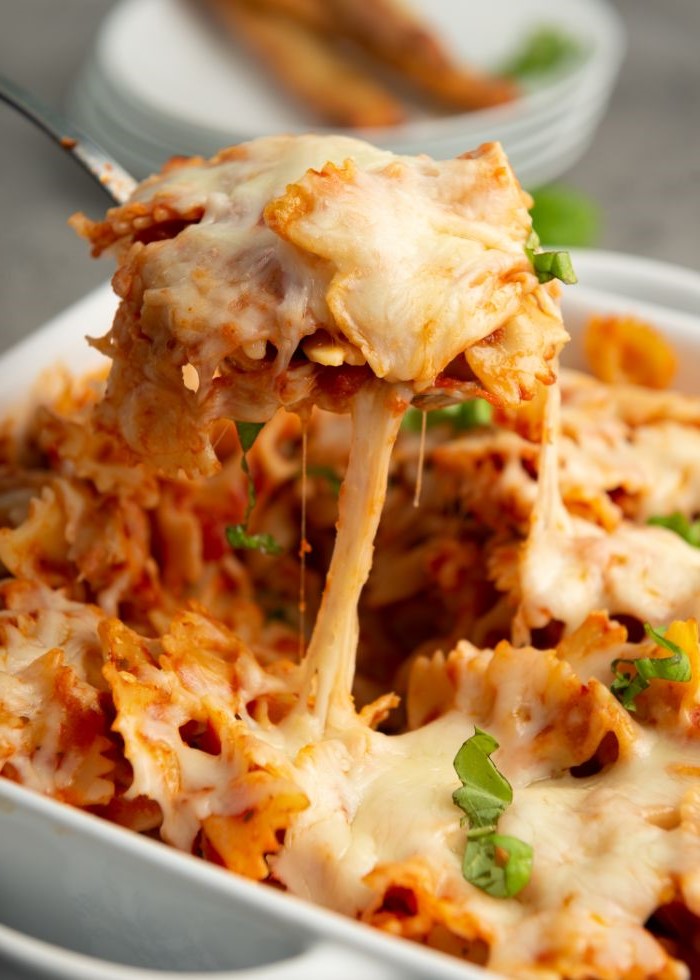 homemade pasta recipe baked pasta in white casserole dish with lots of cheese fresh basil