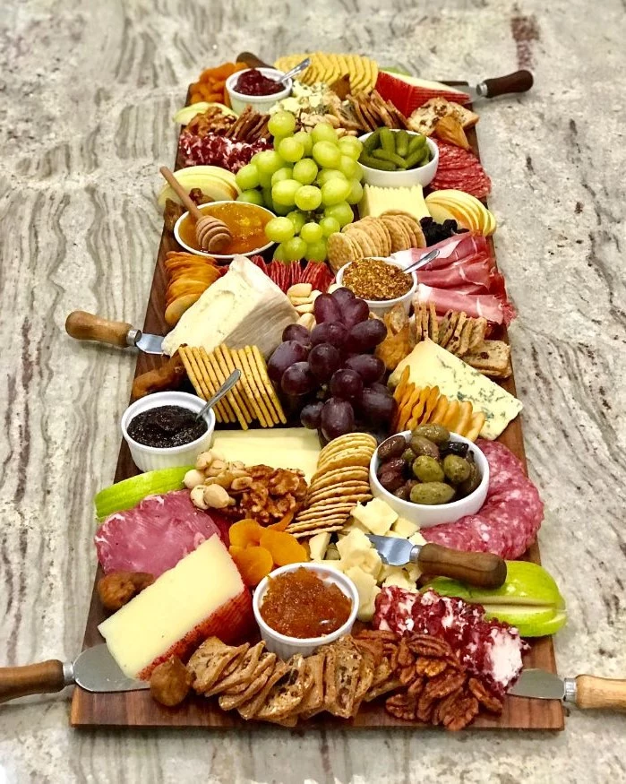 long wooden board with different types of cheese meat what is a charcuterie board crackers fruits
