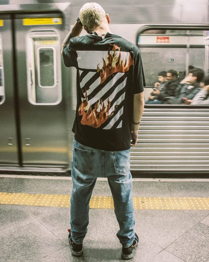 man wearing black off white t shirt jeans black sneakers streetwear fashion in the subway