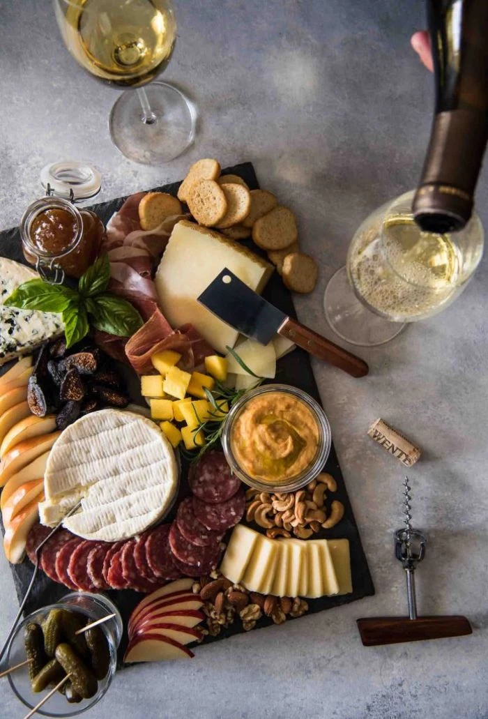 meats cheeses bread fruits nuts condiments arranged on black board what is a charcuterie board