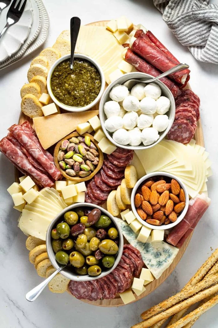 meats cheeses nuts olives bread how to make a charcuterie board arranged on elliptical wooden tray