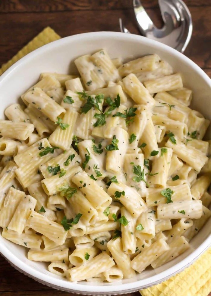 pasta cooked in creamy garlic sauce placed in white bowl homemade noodle recipe garnished with parsley