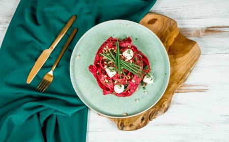 pasta cooked with beetroot sauce placed on white plate pasta dough recipe garnished with baby mozzarella pine nuts wild onion