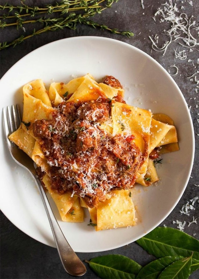 pasta with tomato sauce placed on white plate homemade pasta recipe garnished with grated parmesan cheese