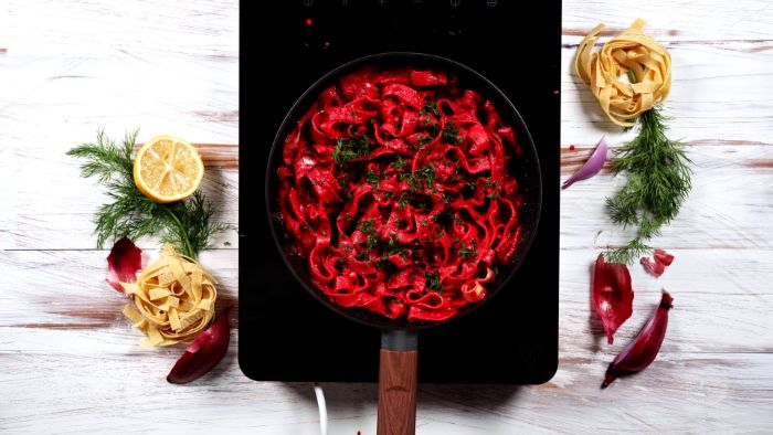 photo from above how to make homemade pasta cooking with red beetroot sauce in black saucepan