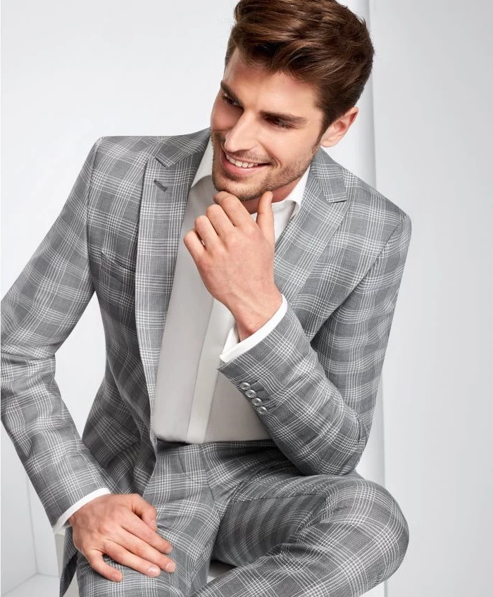 prince of wales light gray suit worn with white shirt fabrics for suits man sitting on a stool