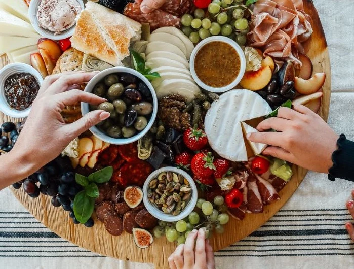 round wooden board charcuterie board ideas different types of cheese meat fruit veggies condiments