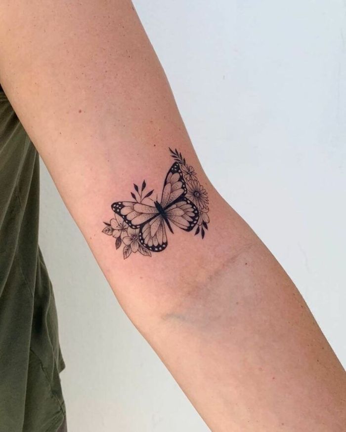 small black and white butterfly with flowers around it butterfly tattoo on arm inside the arm tattoo