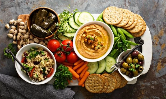 taboule salad hummus olives in bowls what is charcuterie crackers veggies nuts around them
