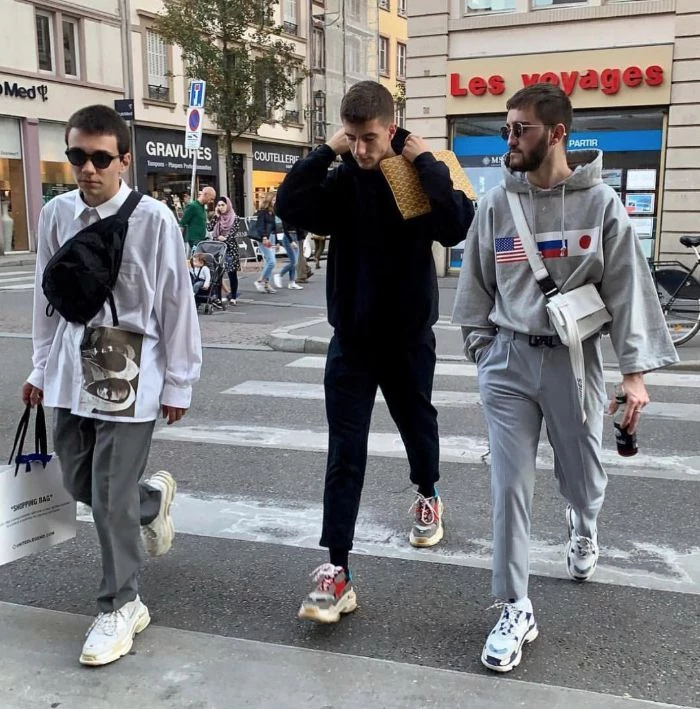 three men walking down the street streetwear outfits wearing black and gray sweaters gray pants sneakers