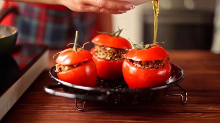 tomatoes stuffed with quinoa mixture finger food appetizers placed on baking dish drizzled with olive oil