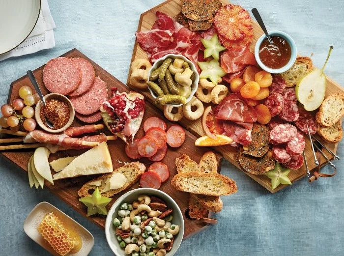 two separate charcuterie board with different types of meat cheese bread fruits honey and nuts