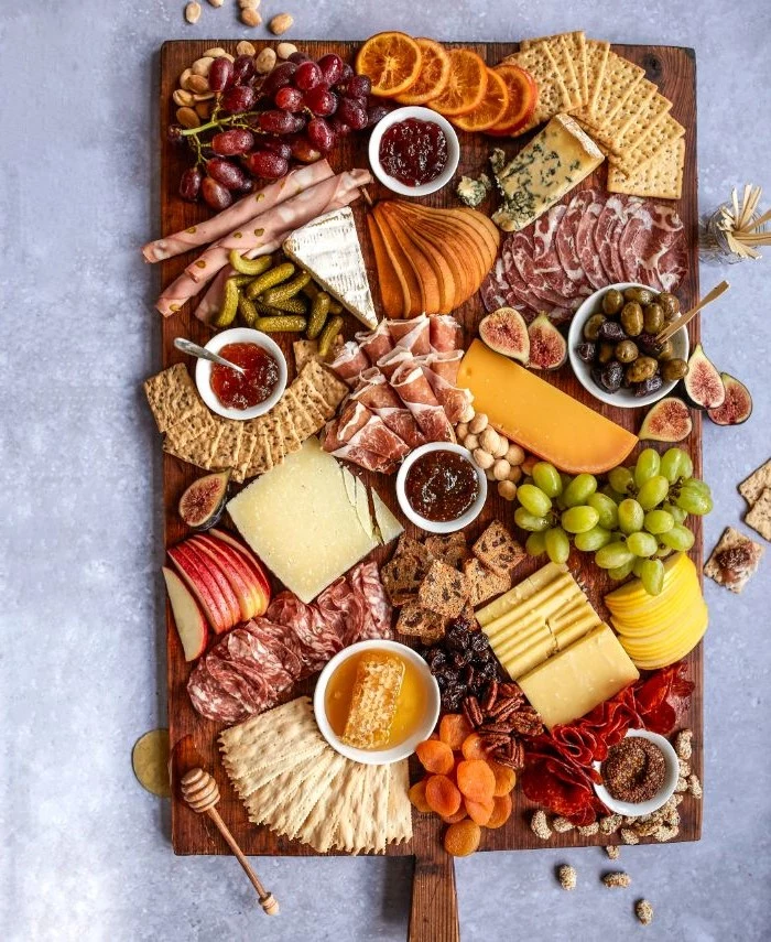 what is a charcuterie board wooden tray covered with types of cheese meat fruits condiments veggies