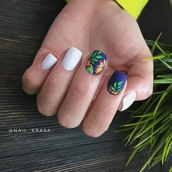 white and blue matte nail polish 2021 nail trends decorations of green leaves orange flowers on middle and index fingers