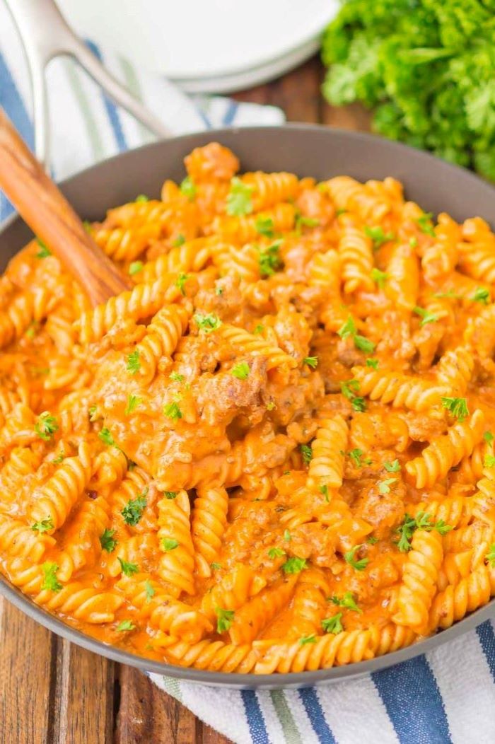 wooden spoon in saucepan best pasta dishes creamy ground beef pasta garnished with parsley