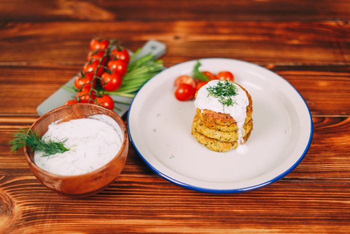 zucchini fritters arranged on white plate best appetizers to bring to a party yoghurt sauce on them with dill