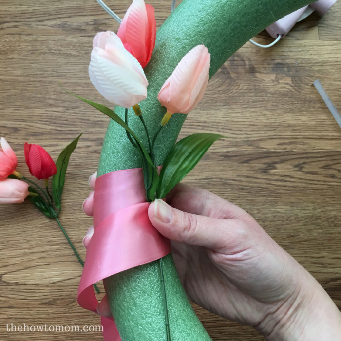 attaching the tulips to the wreath with pink ribbon easter crafts for adults diy tulip wreath step by step tutorial