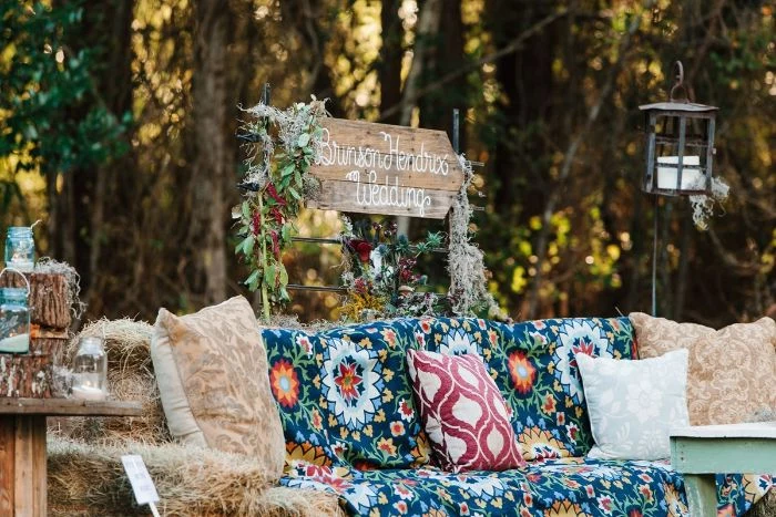 backyard wedding lounge space for photos made of hay with colorful blanket and throw pillows
