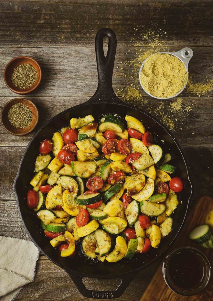 black skillet filled with sautéed squash zucchini and cherry tomatoes squash recipes garnished with parmesan
