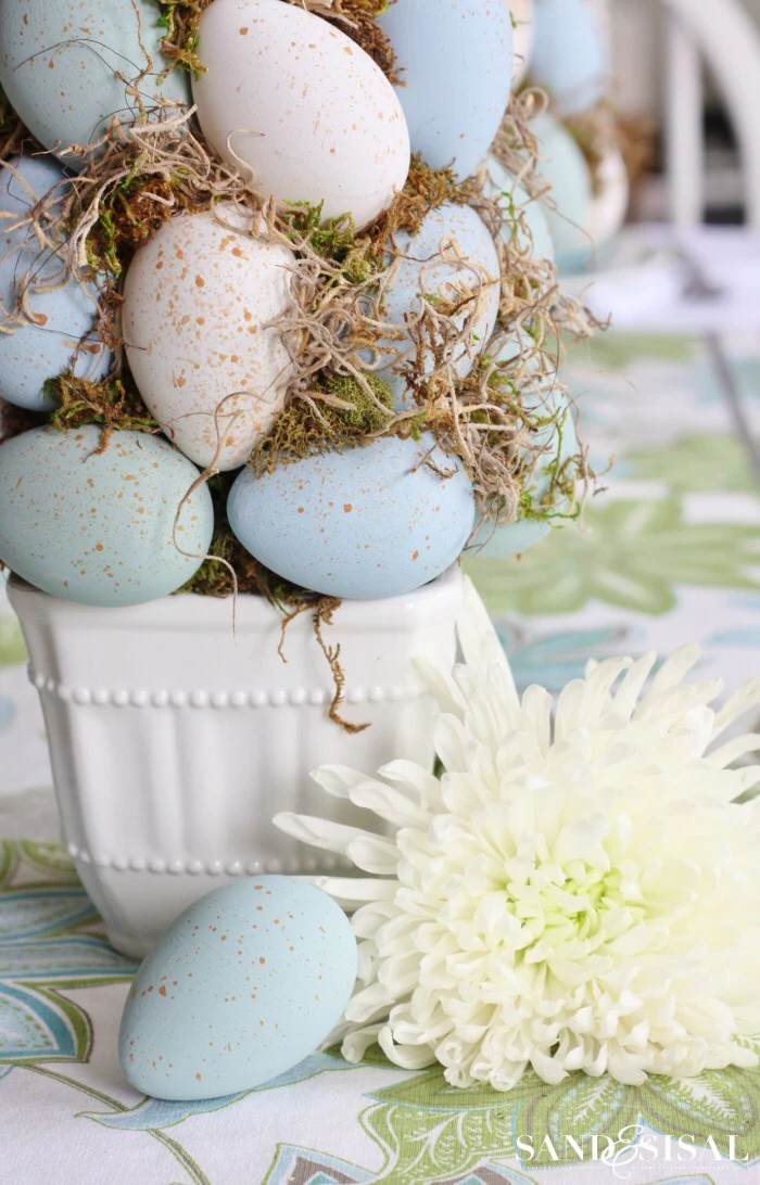 blue and white eggs with moss diy tree topiary easter decorations 2021 white flower next to it