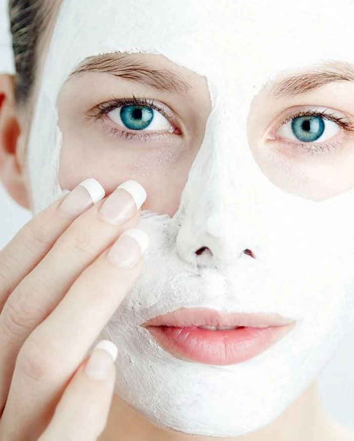 blue eyed woman putting on white face mask diy face mask for acne french manicure on her nails