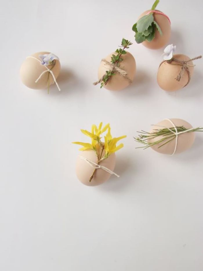 boiled eggs with different flowers tied to them with a strand or bakers twine easy easter crafts white background