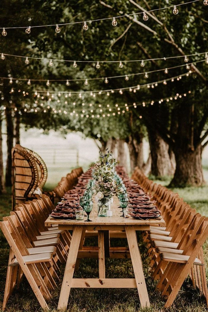 bouquets of spring flowers in the middle of long table surrounded by chairs backyard wedding ideas strings of lights hanging above