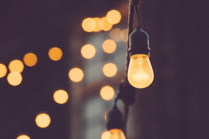 close up photo of light bulb hanging off a string living room design mistakes blurred lights in the background