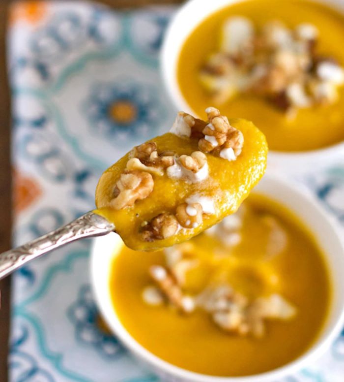 close up photo of spoon filled with summer squash soup and walnuts how to cook squash and zucchini