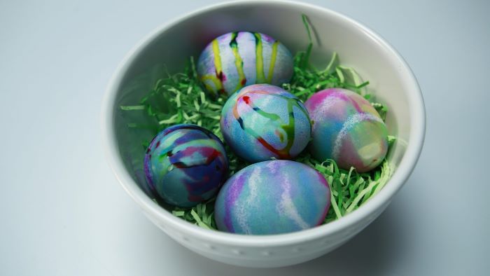 colorful eggs in different colors homemade egg dye placed in white bowl with green paper