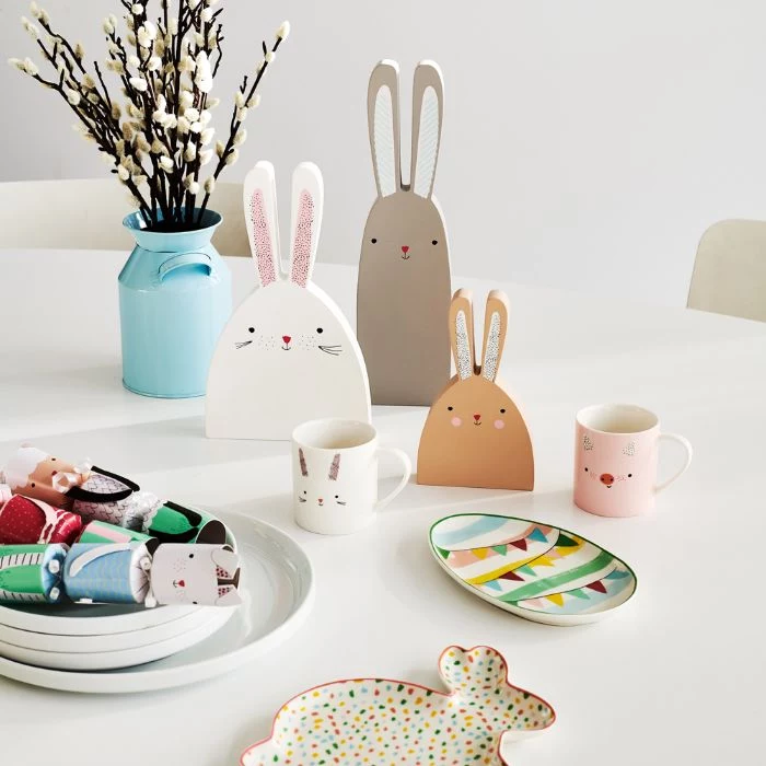 cute bunnies made from carton next to mugs outdoor easter decorations placed on white table