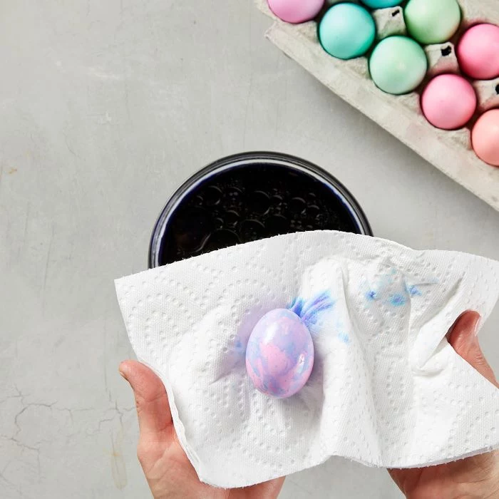 decorated egg being dried with a paper towel how to dye eggs with food coloring step by step diy tutorial