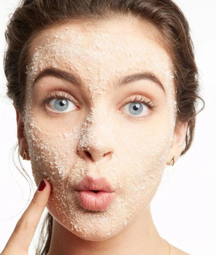 diy face mask for acne blue eyed woman with brown hair putting on exfoliating mask on her face
