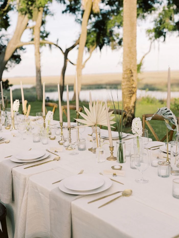 dried flower bouquets on long table with white cloth outdoor wedding decorations tall trees in the background