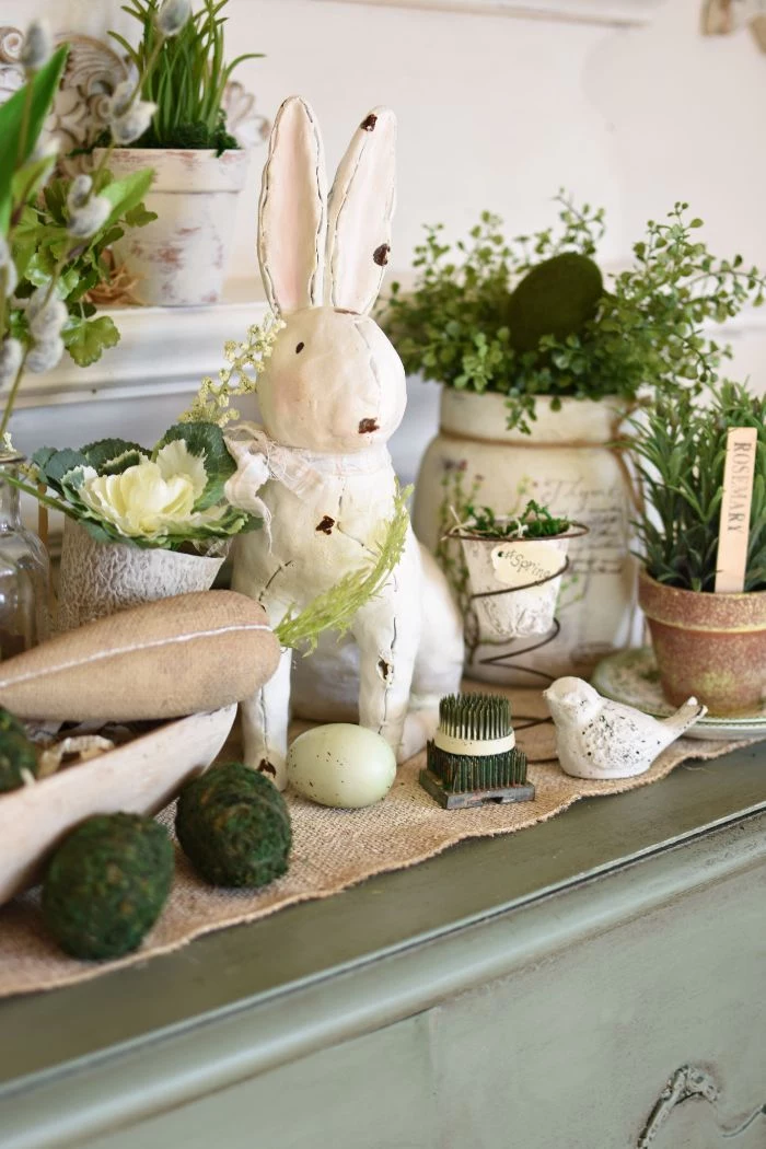 easter decorations ceramic bunny placed in the middle surrounded flowers in ceramic pots