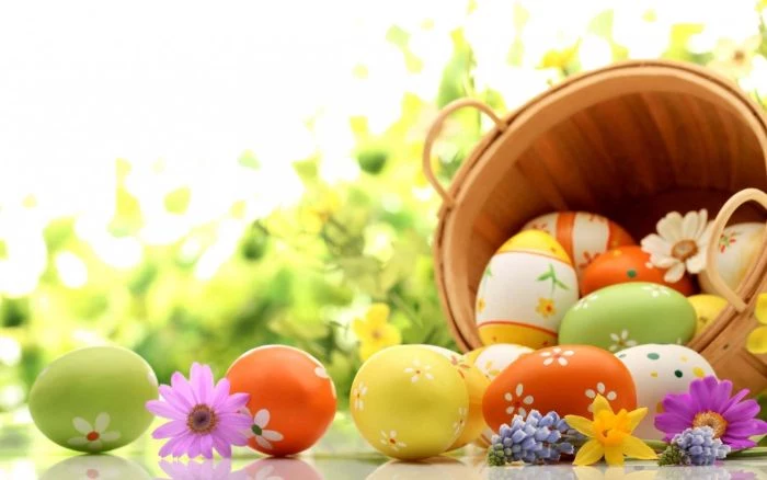 easter egg background wooden basket filled with eggs in yellow orange and green with floral decorations