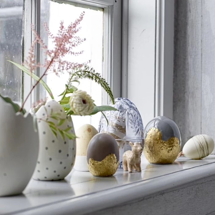 egg shaped vases and figurines placed in front of window with faux flowers easter decoration ideas
