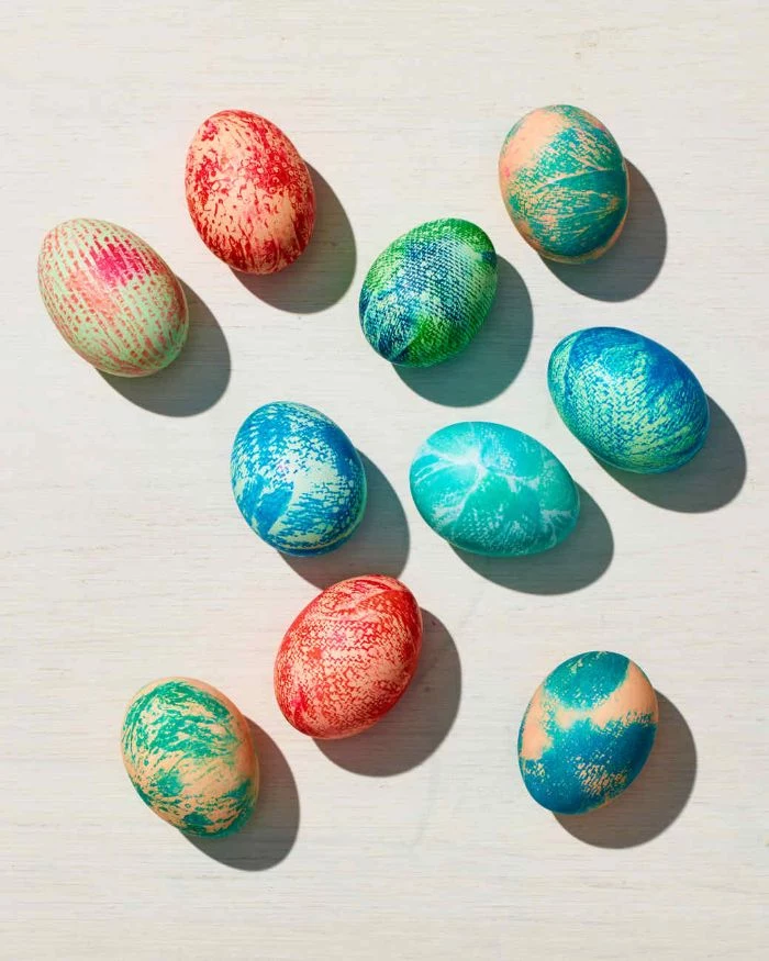eggs decorated in different colors with paper towel how to dye easter eggs scattered on white surface