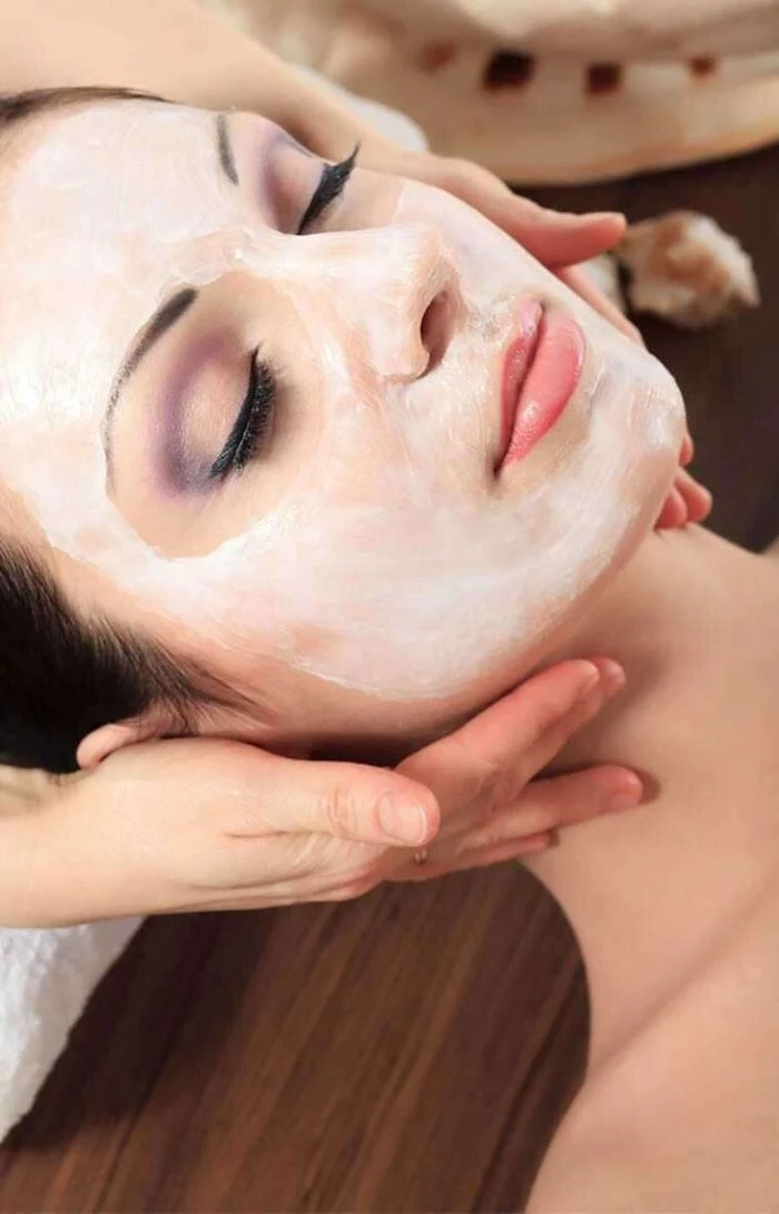 face mask being put on a woman wearing purple eyeshadow hydrating face mask laying down