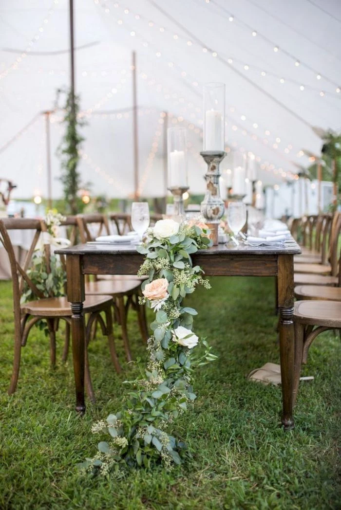 floral table runner on vintage table with vintage chairs around it backyard wedding decorations under white tent