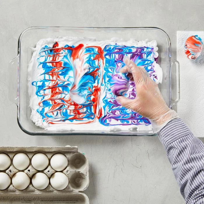 glass tray filled with shaving cream and dye homemade egg dye egg placed in it