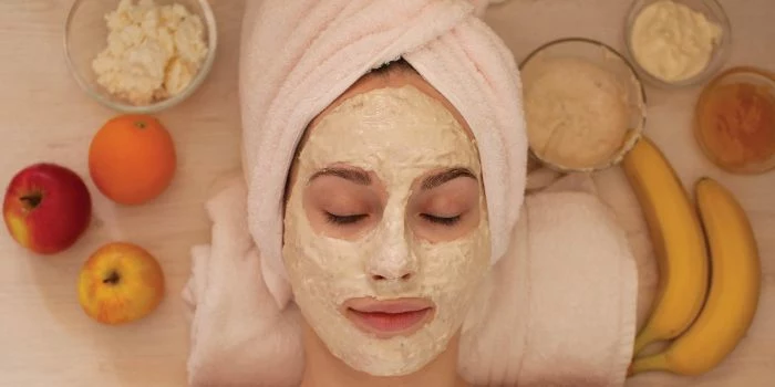 honey face mask woman wearing white towel on her face laying down white face mask on her face